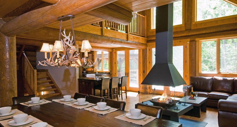 Antler chandelier light over a dining table in a log home