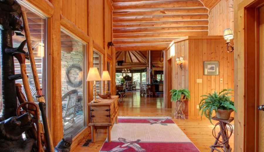 hallway with a rug and plant stands, in a large log home