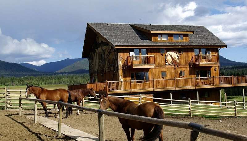 Rustic barn with several horses beside it