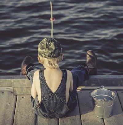 small boy sitting on a dock fishing