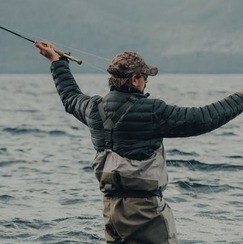 Man fishing near his log cabin lake house